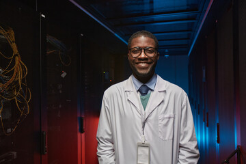 Waist up portrait of African American data scientist wearing lab coat and smiling at camera while...