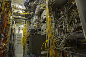 Background image of messy server room with internet cables and wires in heaps, copy space