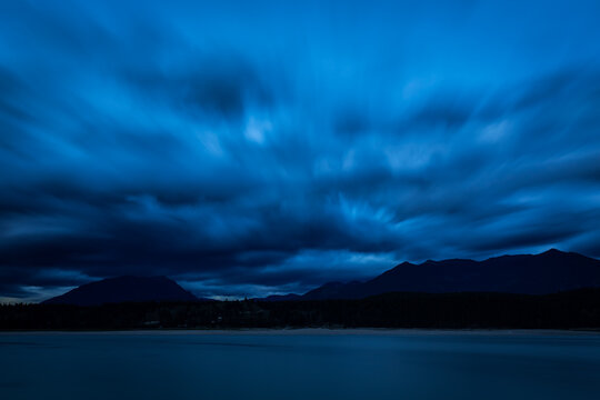Long exposure blue hour landscape with a looming cloudy sky, Lake Koocanusa on the foreground and mountains on the background, British Columbia, Canada