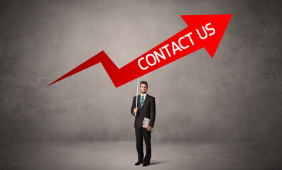 Fototapeta premium Young business person in casual holding road sign with CONTACT US inscription, business direction concept