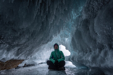 Fototapeta premium A tourist sits in an ice grotto on Lake Baikal