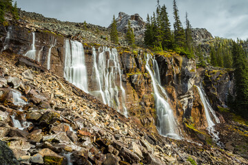 Long exposure of seven waterfalls during autumn, surrounded by rocky mountains and tress, Lake O'Hara, Yoho National Park, British Columbia, Canada