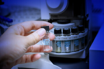 Laboratory concept: close up picture of handhold the sample vial for GC chromatography in chemical...