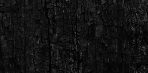 Dark black background of rough burnt wood, soot, and ash. Burn texture.