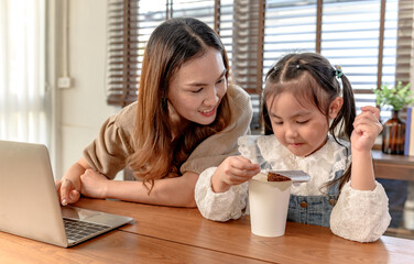 Mom working and teaching daughter for online learning at home. Family togetherness lifestyle and...