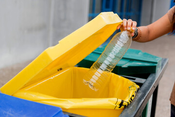 manos una persona, tirando botella de plastico, para su reciclaje, en lugar correspodiente, tacho...