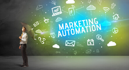Businessman defending with umbrella from MARKETING AUTOMATION inscription, modern technology concept