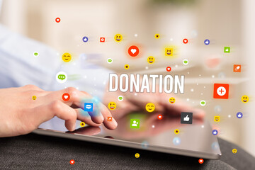 Close up of business person playing multimedia with social media icons and DONATION inscription