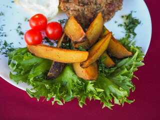 Beefsteak with tomato and herbs on a red background