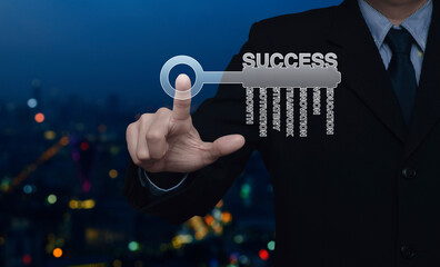 Businessman pressing key icon with business words over blur colorful night light modern city tower and skyscraper, Business success concept