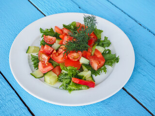 Salad with cucumber and tomato on a blue wooden background