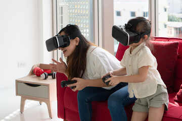 young asian kid and mom playing virtual reality game at home. family together concept