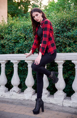 Gorgeous young girl wearing checkered shirt, jeans, topic and shoes in park