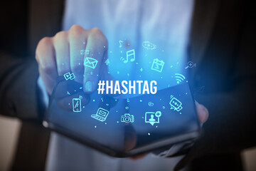 Businessman holding a foldable smartphone with #HASHTAG inscription, social media concept