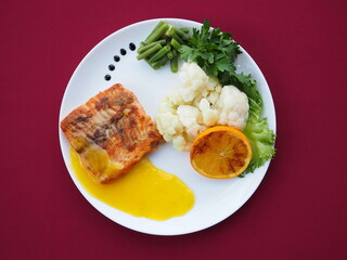 Baked salmon in foil on a red background