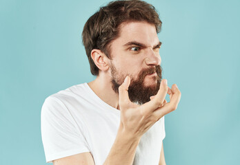 Guy in a white t-shirt brunet on a blue background cropped view puzzled look side view