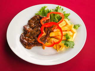 Beefsteak with tomato and herbs on a red background
