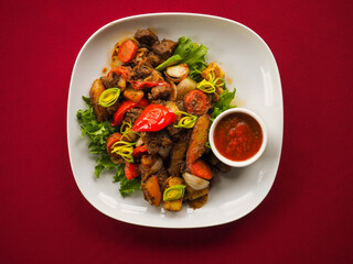 Beefsteak with tomato and herbs on a red background