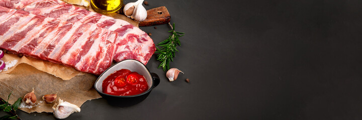 Fresh raw pork ribs seasoned with spices on dark background.