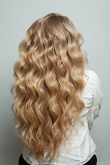 Blonde curly hair. Woman head with long healthy wavy hairstyle