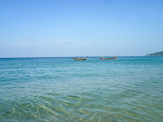 Two wooden boats sail in the Andaman Sea on a sunny summer day.