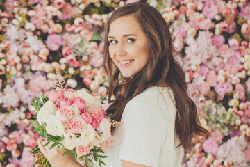 Fototapeta premium Pretty woman smiling and holding rose flowers on floral blossom background