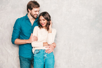 Portrait of smiling beautiful woman with red lips and her handsome boyfriend. Happy cheerful family posing in studio near gray wall.Valentine's Day. Models hugging. Concept of love