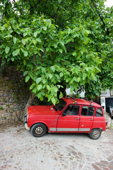 vintage red car under the tree on the street of old town in Macedonia