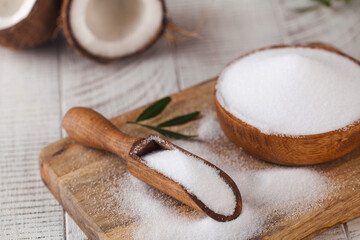 Sugar substitute in a wooden bowl on a background of coconut. Natural sweetener. Stevia, erythritol.