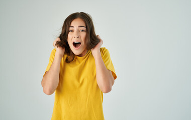 emotional woman in yellow t-shirt holding hair studio cropped view
