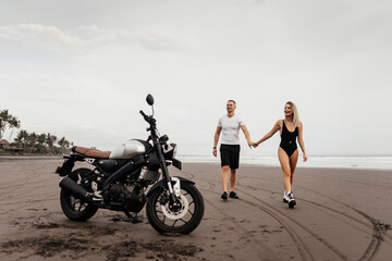 Fototapeta na wymiar Young couple riders together on sand beach by motorbike - travel concept