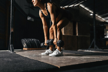 Fit young woman at a crossfit style on dark gray background. Fitness, functional, training, and lifestyle concept