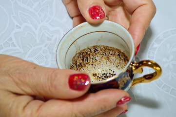 close-up - a fortune teller holds a small coffee cup in her hands, guessing by the coffee grounds