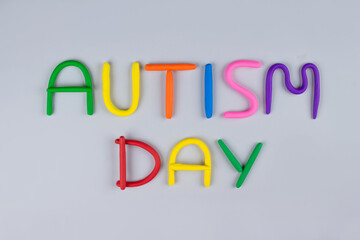 World Autism Awareness Day concept - multicolored letters made of play-doh or other sensory playfoam on light gray background. Autism spectrum disorder and child mental health concept, selective focus