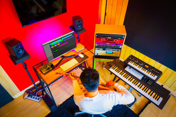 top view of asian male musician recording guitar track in home studio