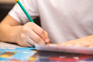 boy of six years writes with a pencil sitting at the table. close-up