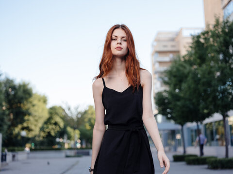 Fashionable Woman in a black dress walks down the street in the park in nature