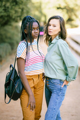 Two Multiethnic women looking at camera together on the street.