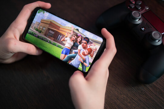 Los Angeles, California, USA - February 21, 2021: Boy holds the phone with The Sims Mobile on the display screen