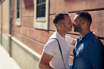 Gay couple kissing outdoors in urban background.