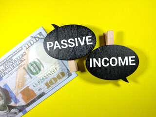 Selective focus.Word PASSIVE INCOME on wooden board with banknote on yellow background.Business concept.