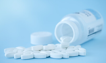 White capsules in bottle on blue background	
