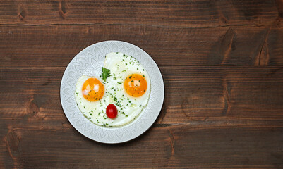 Plate with fried eggs on brown wooden table