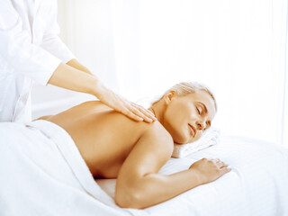 Obraz na płótnie Canvas Beautiful blonde woman enjoying back massage in spa center. Beauty and lifestyle