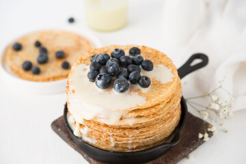 Homemade thin traditional pancakes with condensed milk and blueberries, selective focus