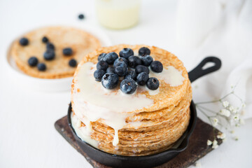 Homemade thin traditional pancakes with condensed milk and blueberries, selective focus