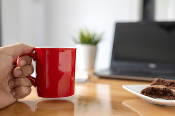 Man hand holding red coffee cup on blurred desk background. TAKE A BREAK Coffee Cup Concept.