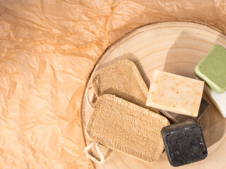 Solid shampoo soap conditioner bar, natural body care eco friendly products and loofah sponges on wooden board and beige neutral paper