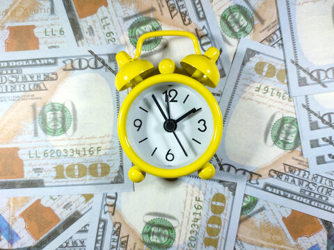 Selective focud.A yellow alarm clock on dollar banknote backround.Money time concept.