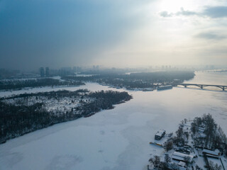 The frozen Dnieper river in Kiev. Aerial drone view. Winter frosty morning. The sun breaks through the clouds.